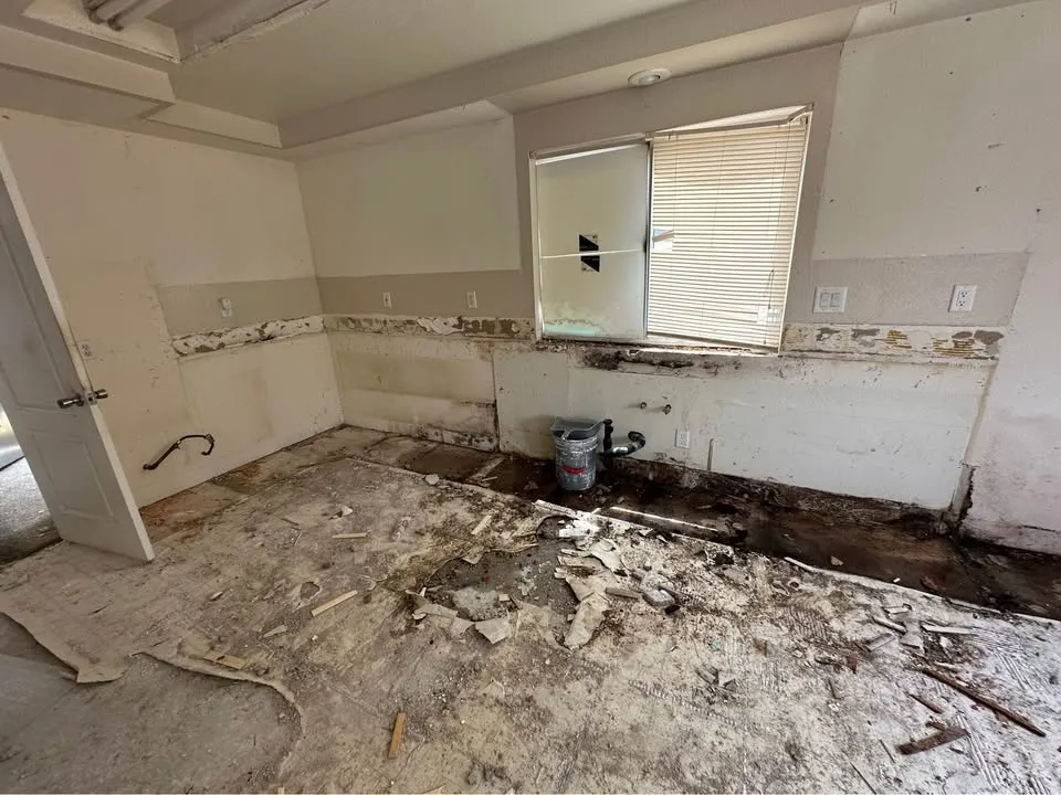 Kitchen with cabinets and countertop removed and the tile line left on the wall
