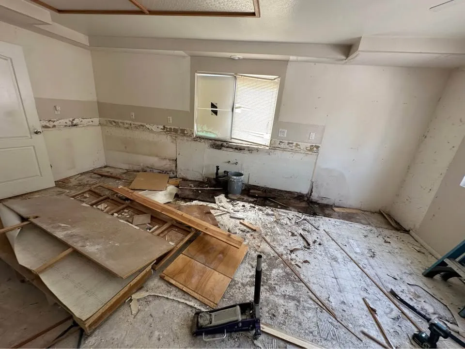 Kitchen with cabinets removed and wood flooring pried up