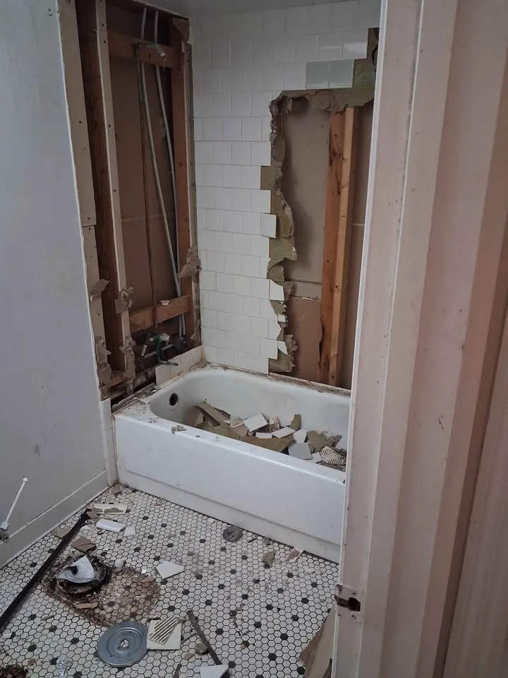Bathroom with wall tile removed around the tub and studs exposed