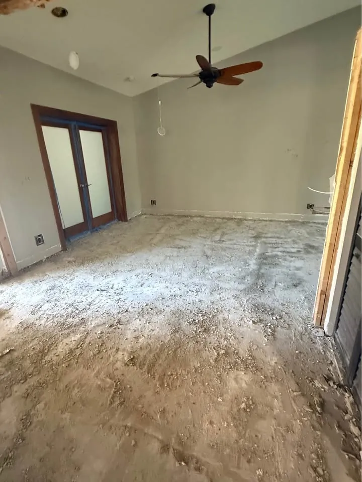 Bedroom with flooring pulled up and the ceiling fan still in place