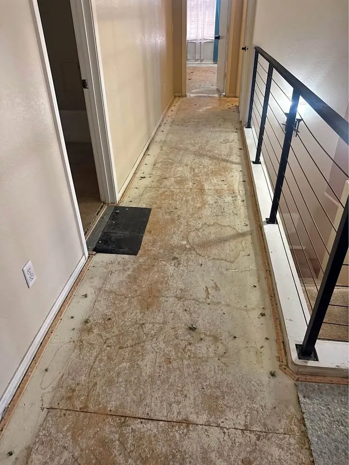 Upstairs hallway with flooring removed beside a cable railing