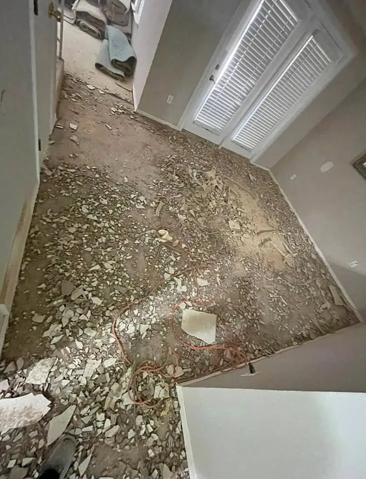 Room with the floor covered in broken tile and mortar