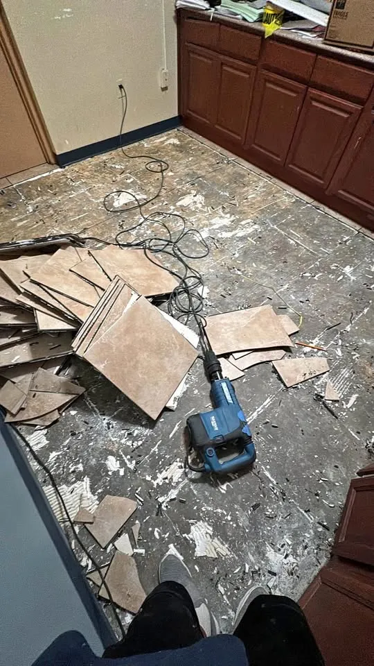 Kitchen floor tile being broken up beside wood cabinets