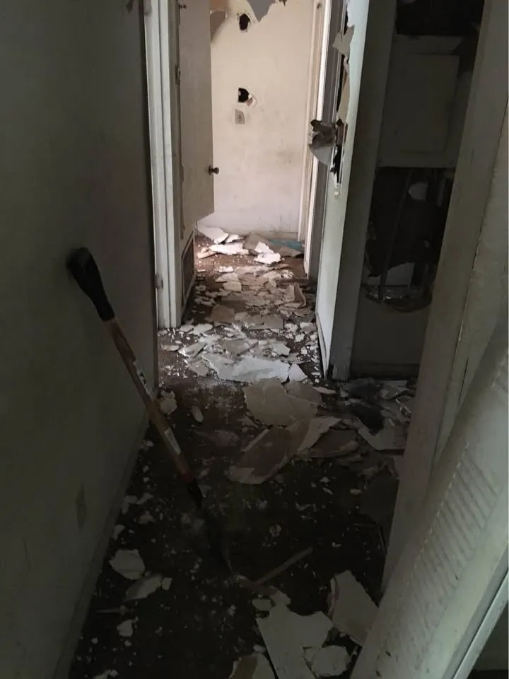 Narrow hallway covered in broken tile debris