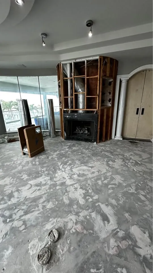 Living area with flooring removed and a built-in wall unit exposed