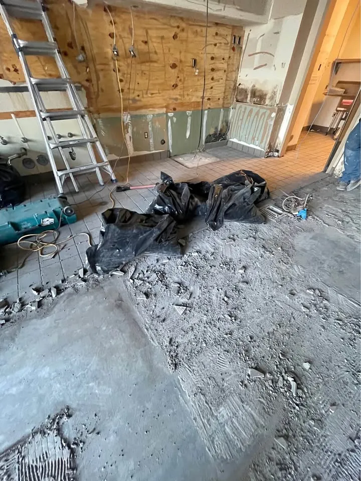Commercial kitchen with wall tile stripped and broken floor tile bagged