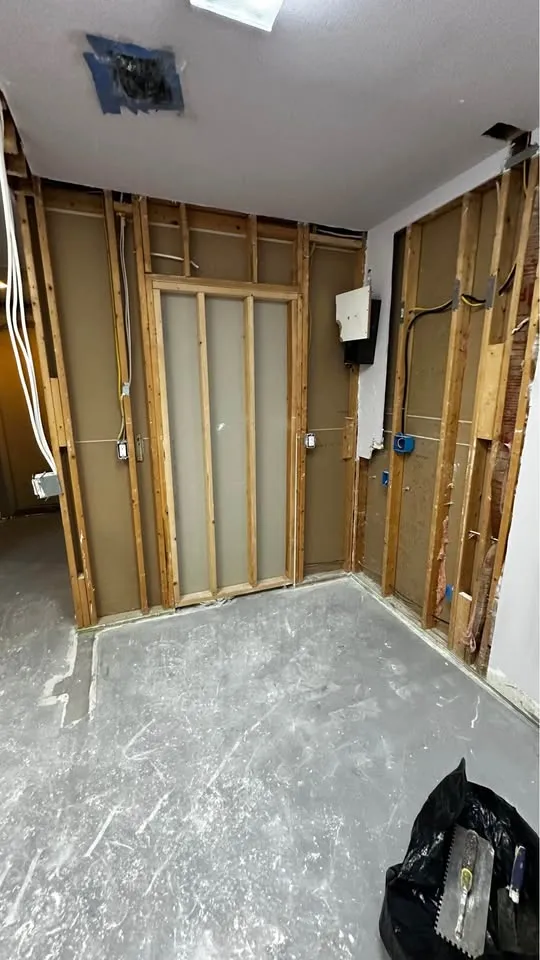 Laundry area stripped to studs with plumbing lines exposed, which must be made safe before demolition