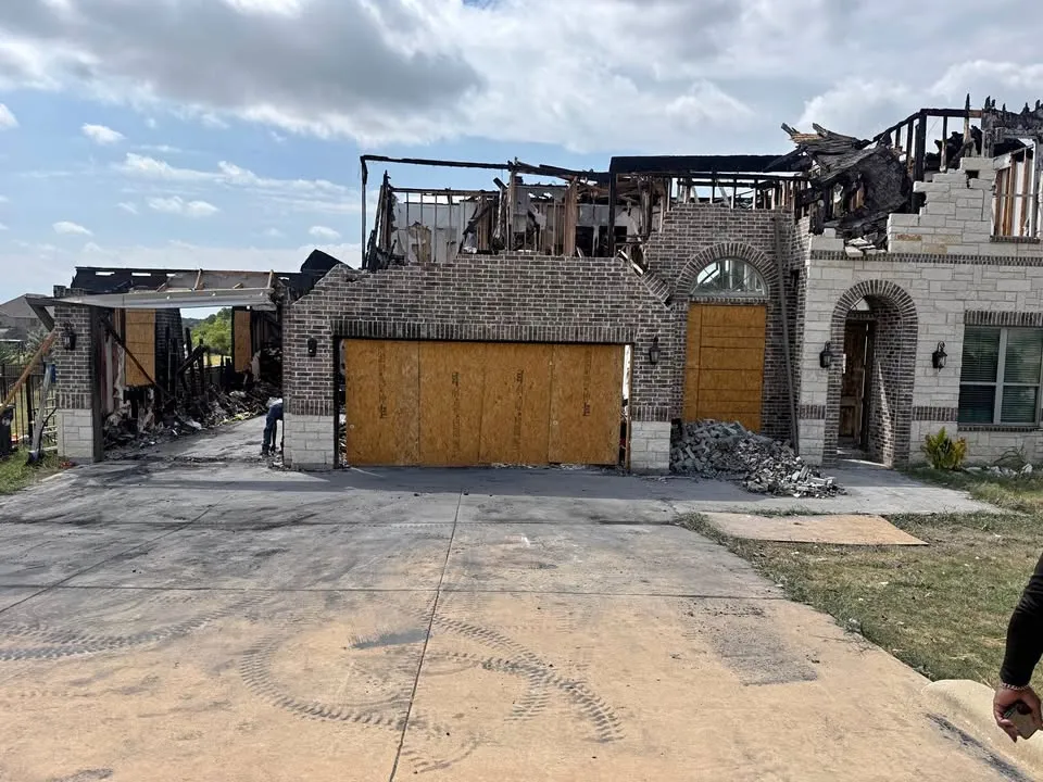Fire-damaged two-storey house with the roof burned away above the garage