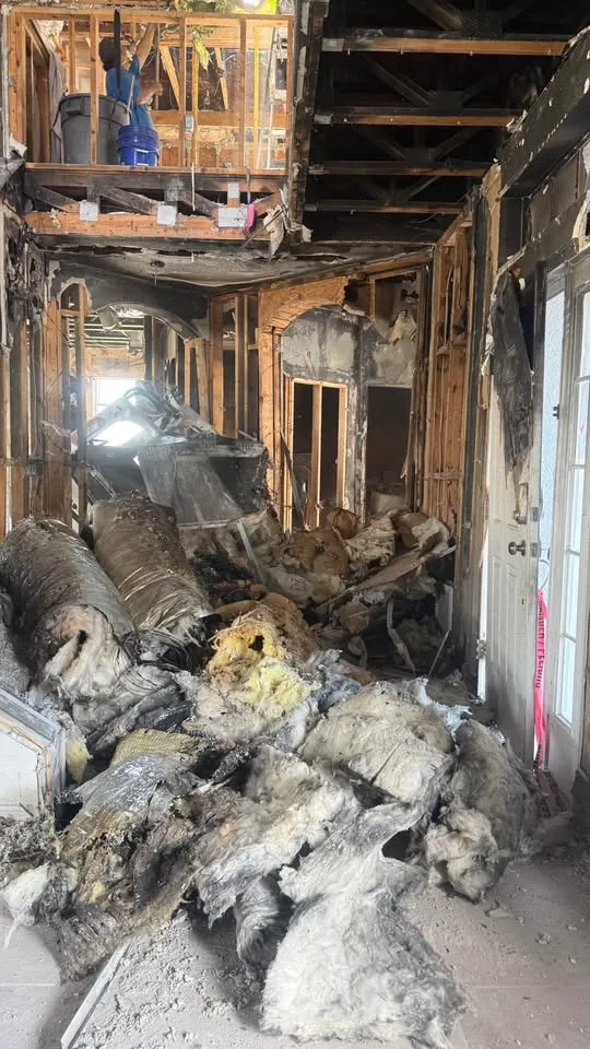 Burned-out room stripped to framing with heavy debris
