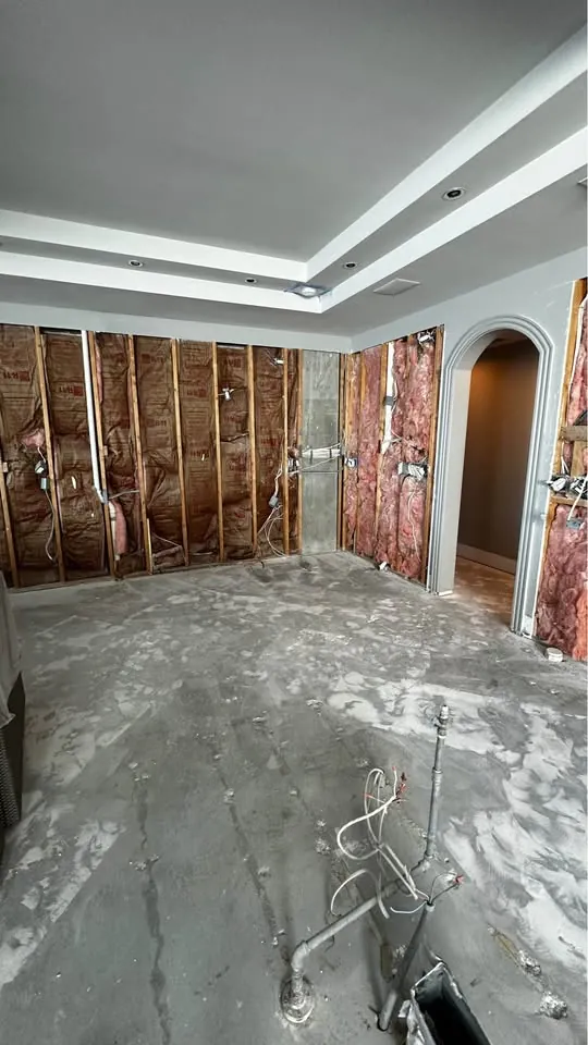 Room with walls opened to insulation and the floor stripped to concrete
