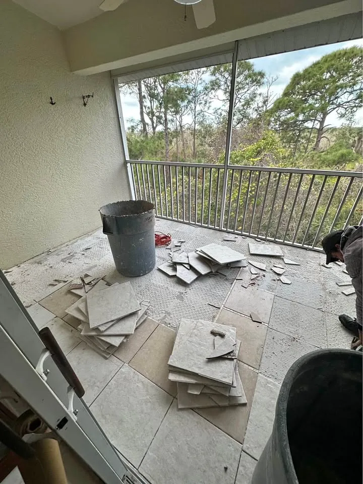 Screened balcony with floor tile being lifted into buckets