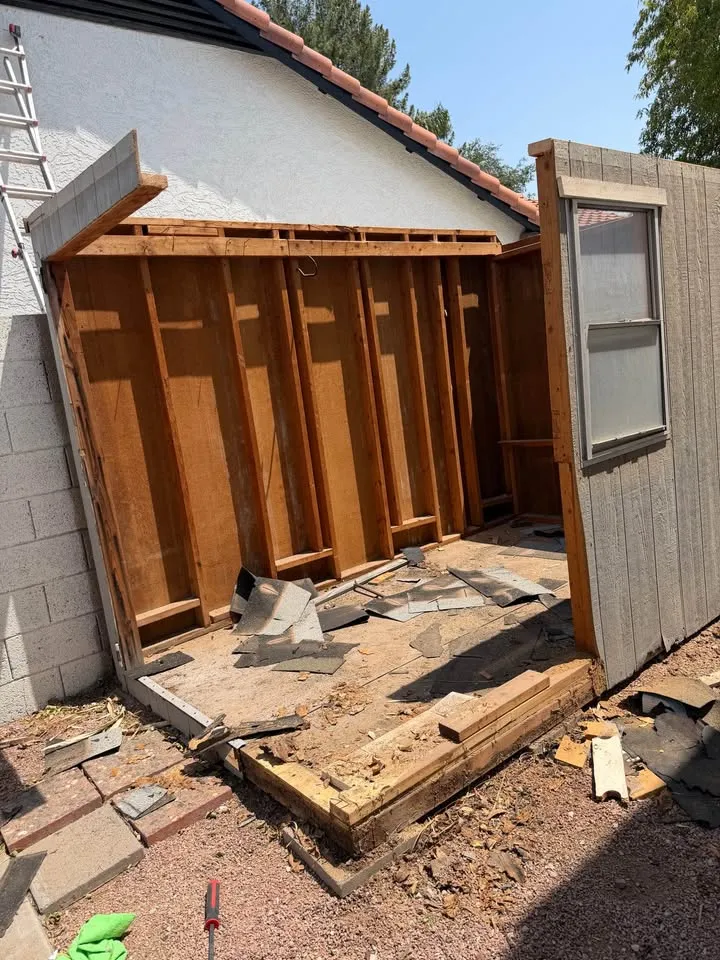 Small structure beside a house taken down to its base with debris ready for clean-up before inspection