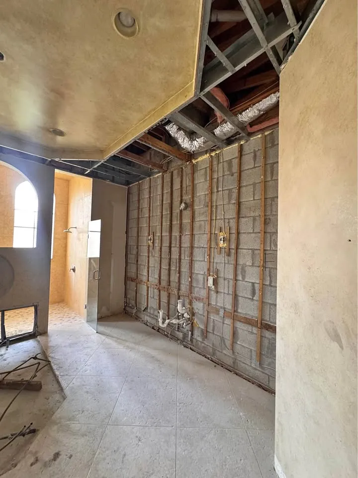 Room with drywall stripped from a block wall and the ceiling partly opened