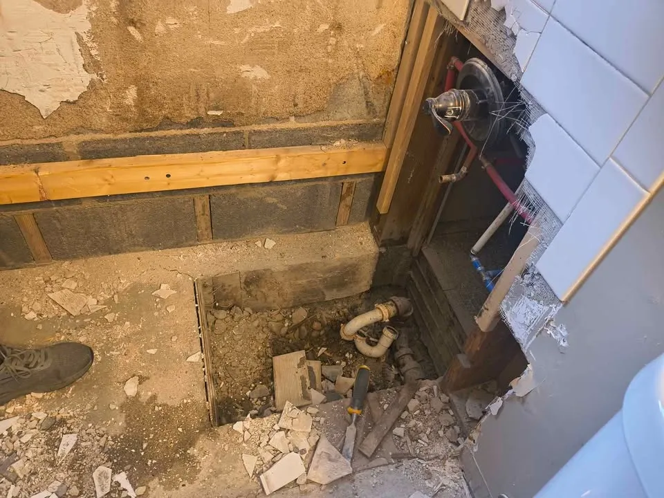 Shower base broken out down to the drain with the block wall exposed