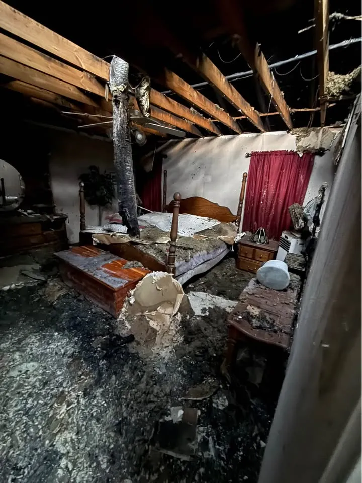 Fire-damaged bedroom with the ceiling burned open