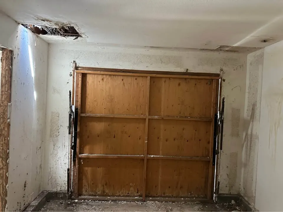 Garage interior with stained drywall and a boarded garage door