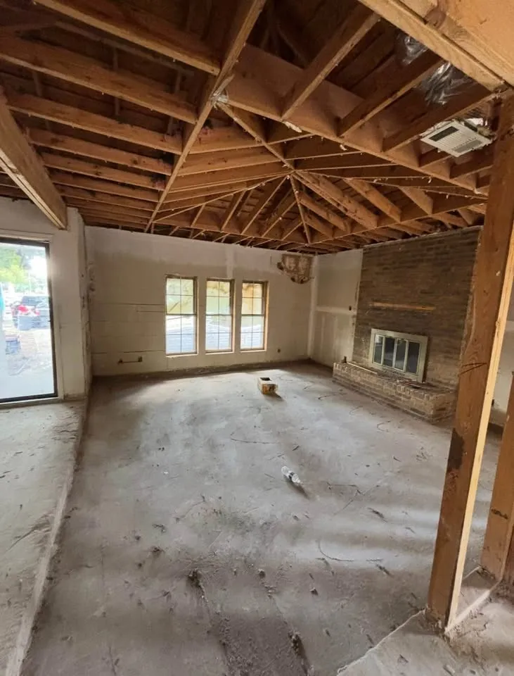 Living room with the ceiling removed to the roof rafters and a brick fireplace
