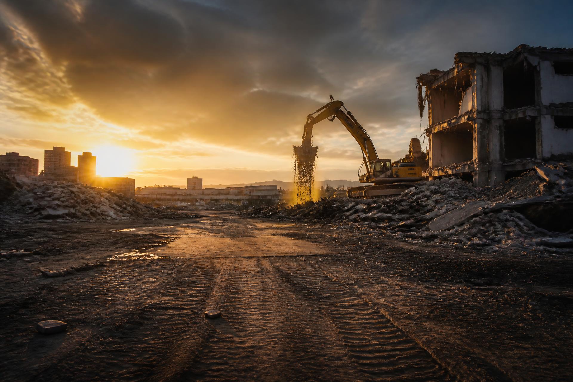 Excavator finishing a demolition teardown on a cleared Toronto site at golden hour